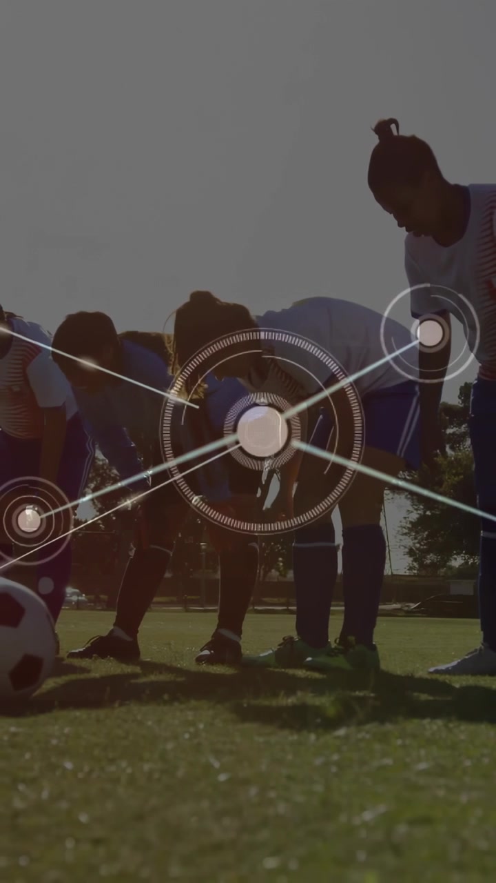 Vertical video: Women soccer players bending by ball, cone, starting HUD lines linking for training