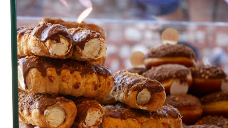 close-up shot of chocolate-covered cream pastries stacked in a bakery window