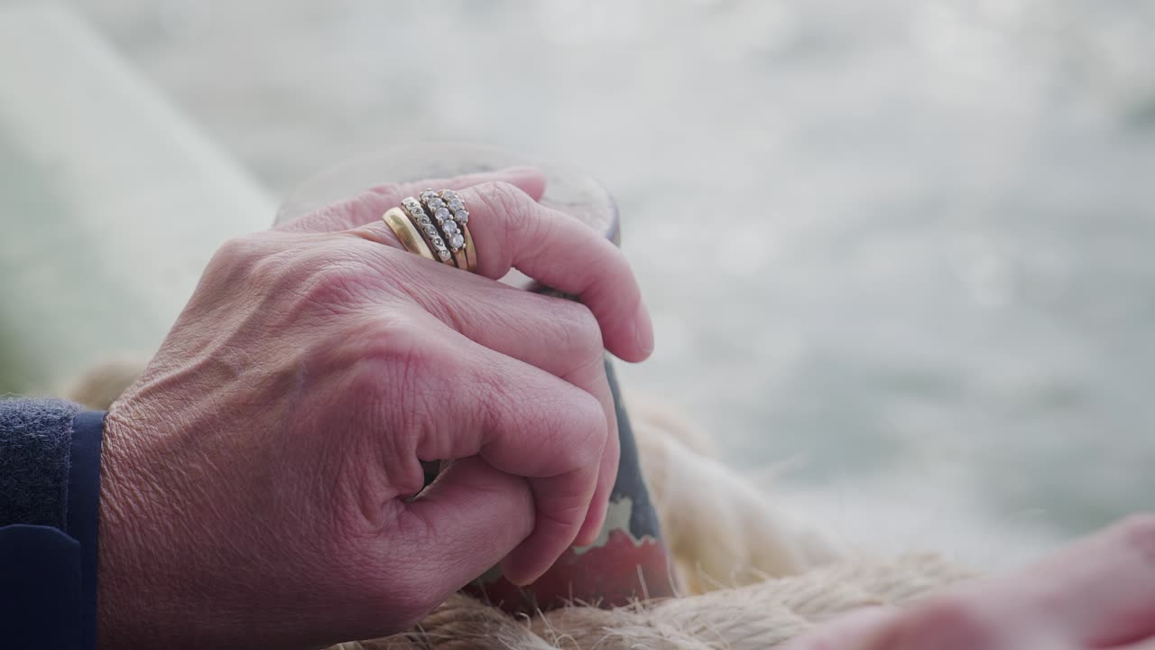 Married Woman’s hand rests on ferry boat rail showing jewellery rings