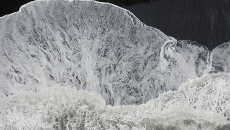 aerial: top down aerial view of waves breaking οn reynisfjara black sand beach in iceland