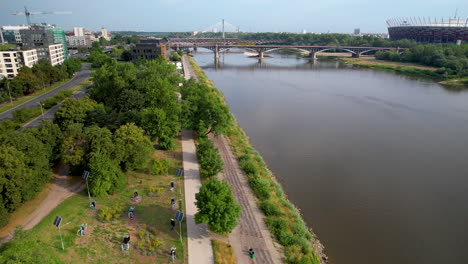 Park-and-walkway-next-to-Vistula-river-with-Poniatowski-bridge,-Warsaw,-Poland