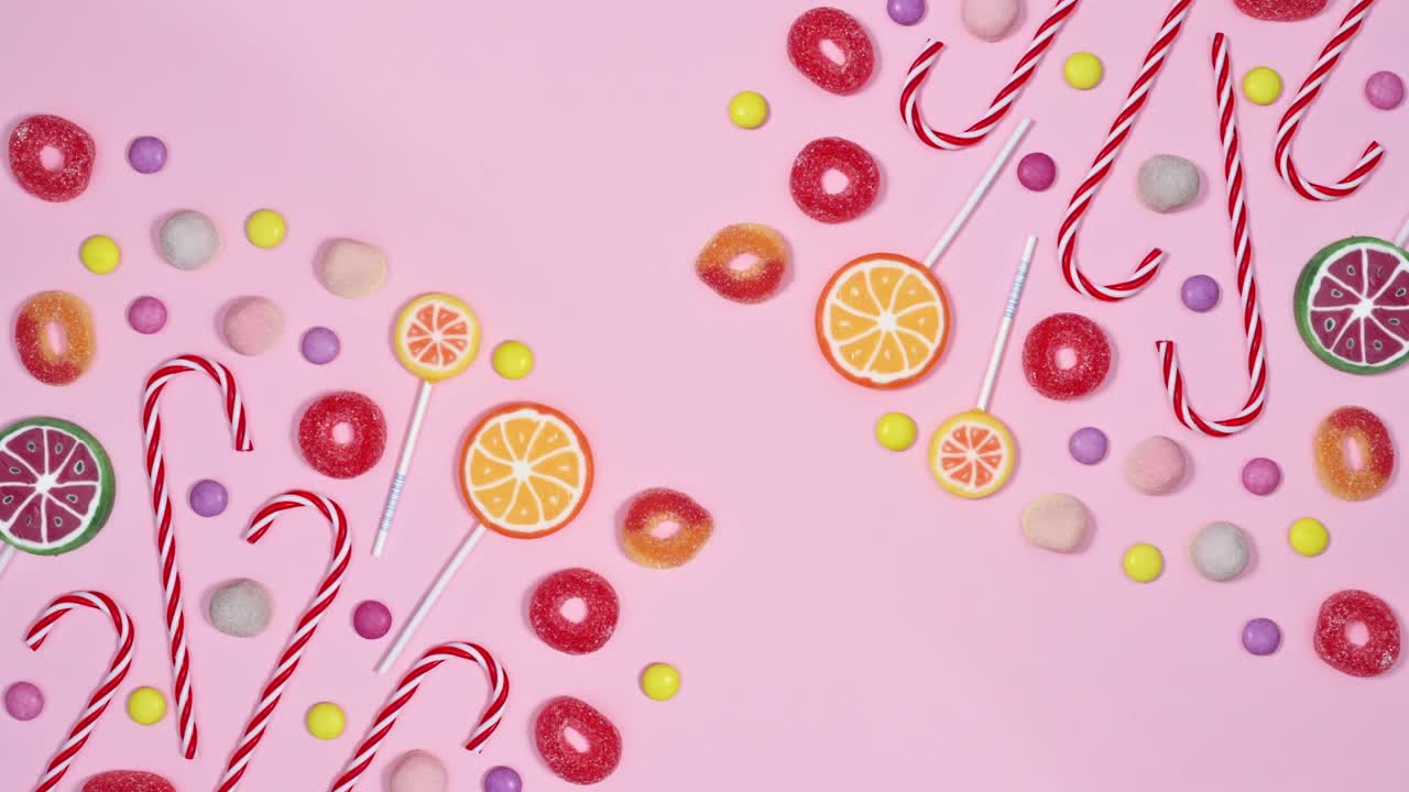 los dulces y las piruletas se mueven en un fondo rosa pastel con espacio de copia.