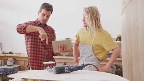 Zwei-Kaukasische-Männliche-Surfbrettbauer-Stehen-Und-Arbeiten-Mit-Einem-Tablet-An-Projekten