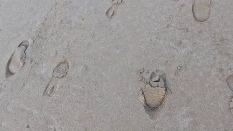 huellas de zapatos esparcidas por la superficie de la playa de arena