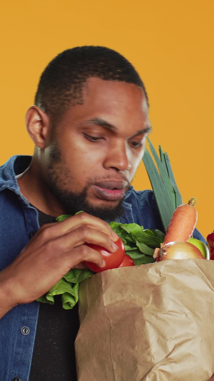 Jovem afro-americano inspecionando alimentos frescos em uma sacola de papel