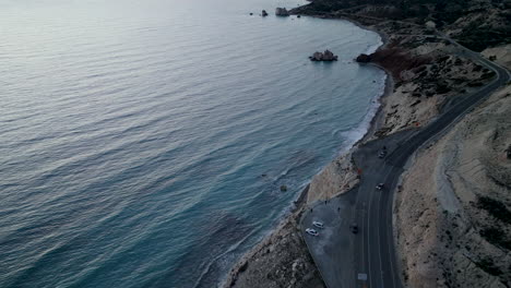 aerial - coastal road near aphrodite's rock in paphos, cyprus, at dusk