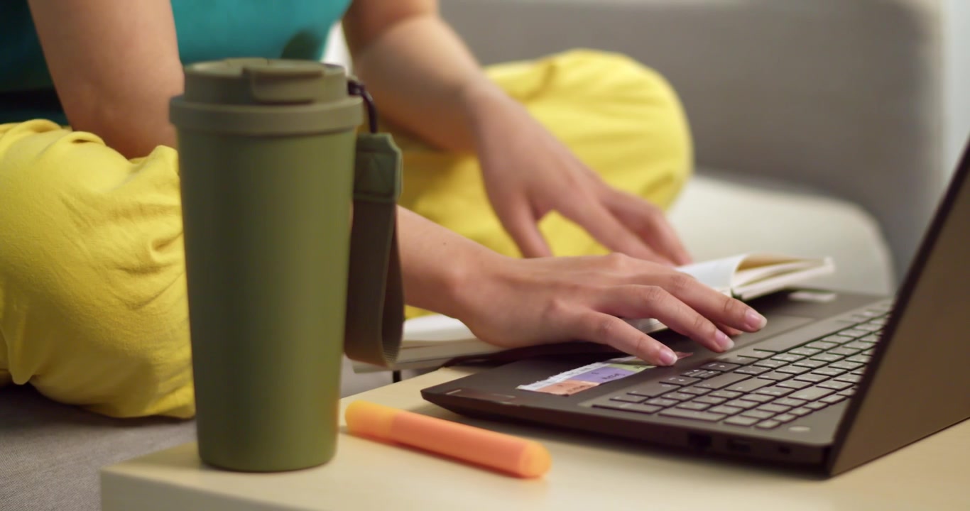 Un individuo rilassato digita su un laptop sorseggiando caffè in un ambiente domestico confortevole.