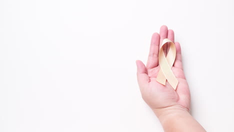 detail of male hand holding orange ribbon over white background