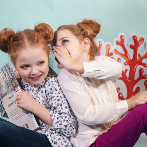 two little girls reading a book on a blue background. friends. childhood. friendship. fairy tales. square video