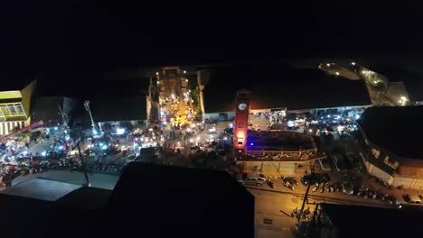 Aerial-Footage-of-The-Vietnamese-Memorial-Clock-Tower-in-Nakhon-Phanom-Province,-Thailand-Surrouned-by-Lively-Night-Walking-Street