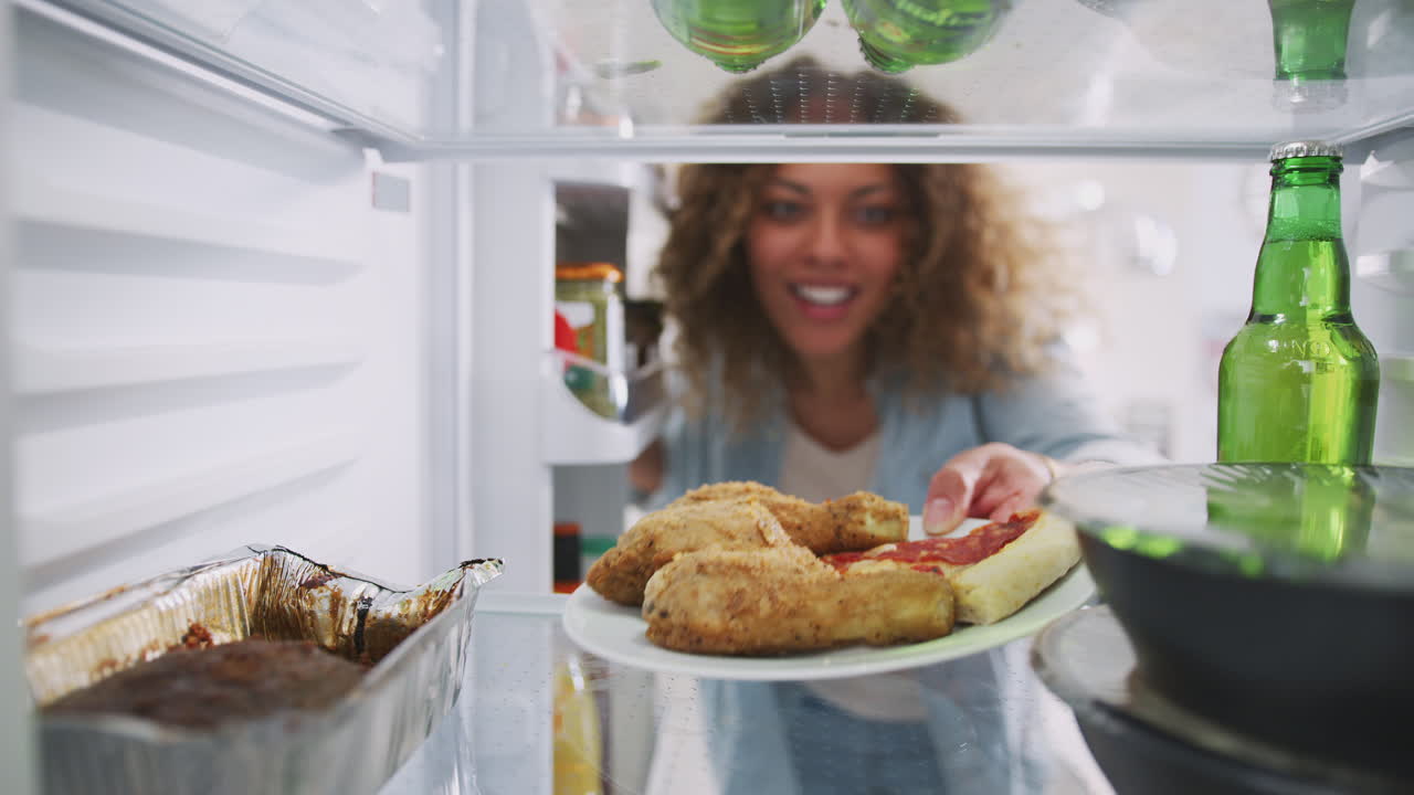 vista mirando desde el interior del refrigerador lleno de comida para llevar cuando la mujer abre la puerta