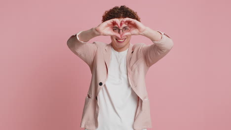 smiling young man makes heart gesture demonstrates love sign expresses good feelings and sympathy