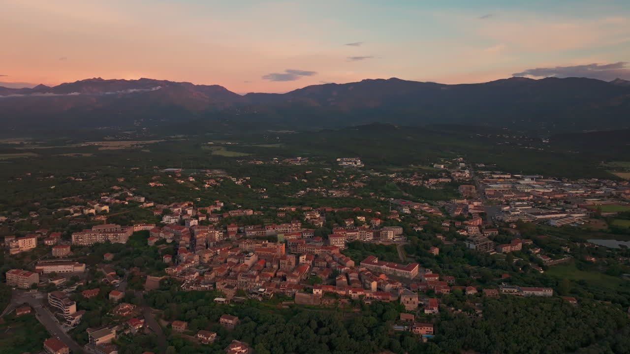 Aerial drone shot of the old town of Porto vecchio, Corsica, France at sunrise. High view of the citadel and the harbor. Warm colorful sky before the sun rises. First lights, golden hour