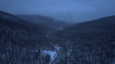 beautiful aerial drone video footage of a mountain road through the appalachian mountains covered in snow at night during evening