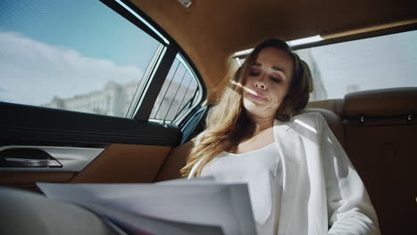 tired business lady reviewing data in car. woman reading documents in automobile