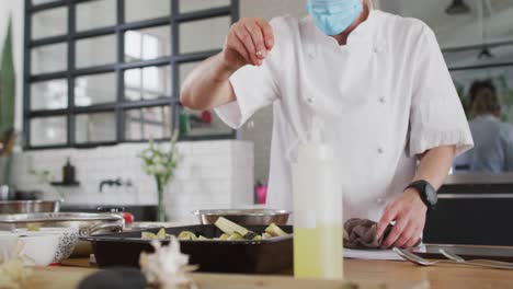 cocinera caucásica que enseña a un grupo diverso usando máscaras faciales