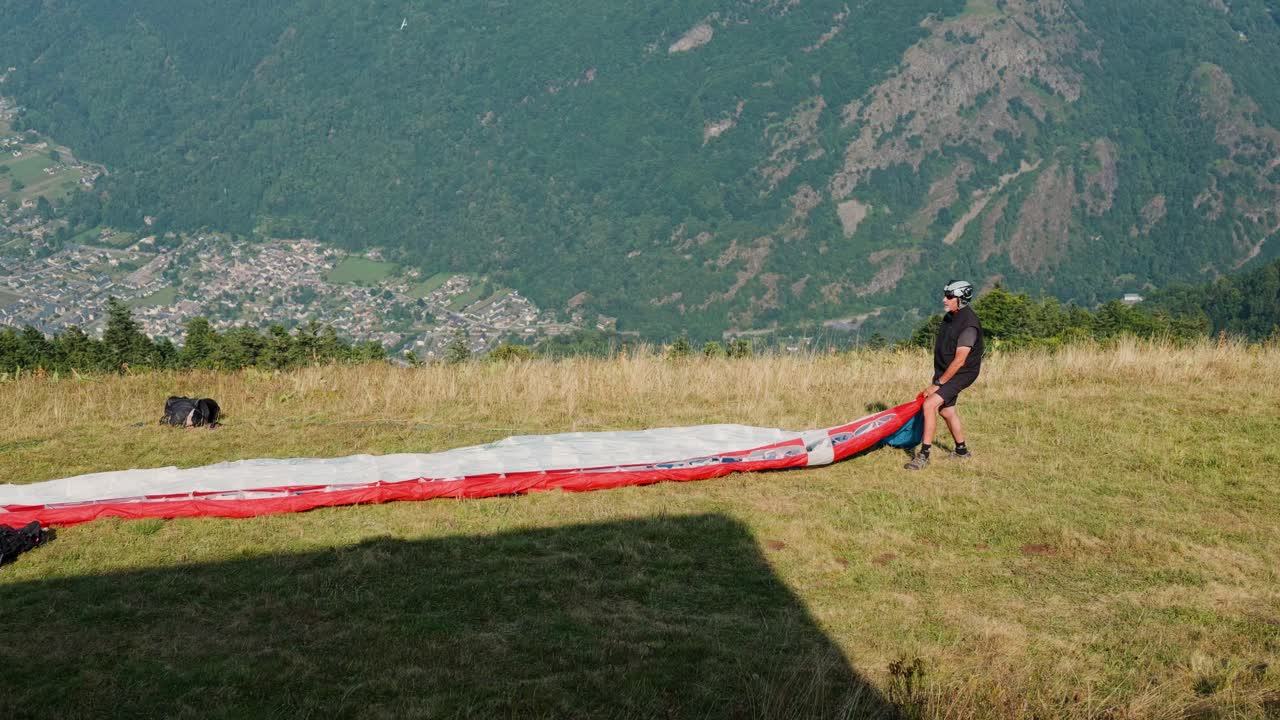 Preparing to paraglide in Luchon, France, overlooking scenic mountains and village below