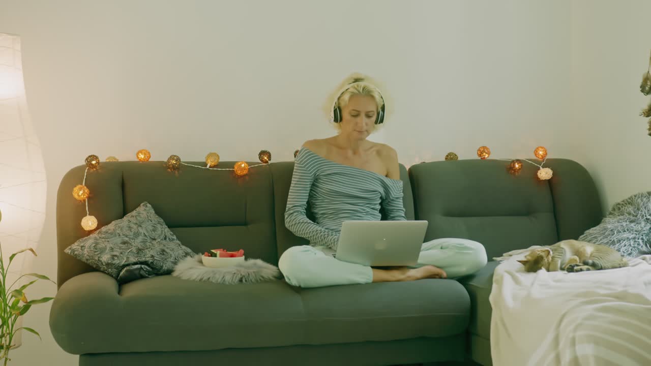 Woman working from home on couch with headphones