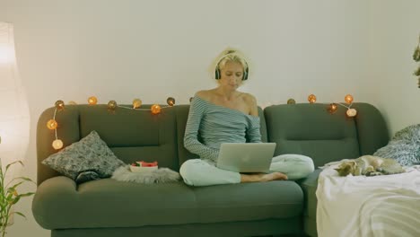 woman working from home on couch with headphones