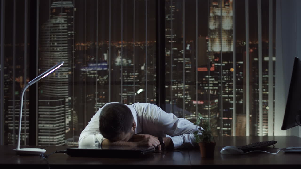 Exhausted Businessman Asleep at Desk in Late Night Office