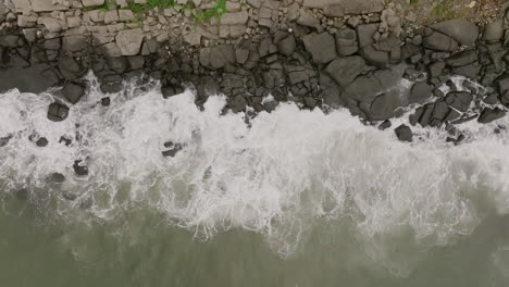 Imágenes-Aéreas-Estáticas-En-Cámara-Lenta-De-Arriba-Hacia-Abajo-De-Las-Olas-Del-Océano-Chocando-Contra-Las-Rocas