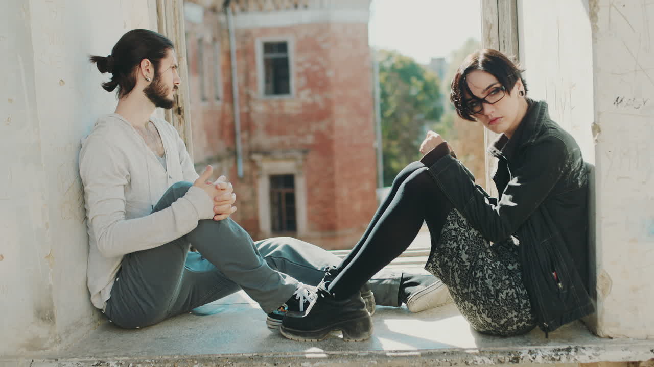 superar la crisis en la relación, el hombre y la mujer jóvenes se toman de la mano y se sientan en un alféizar en un aba