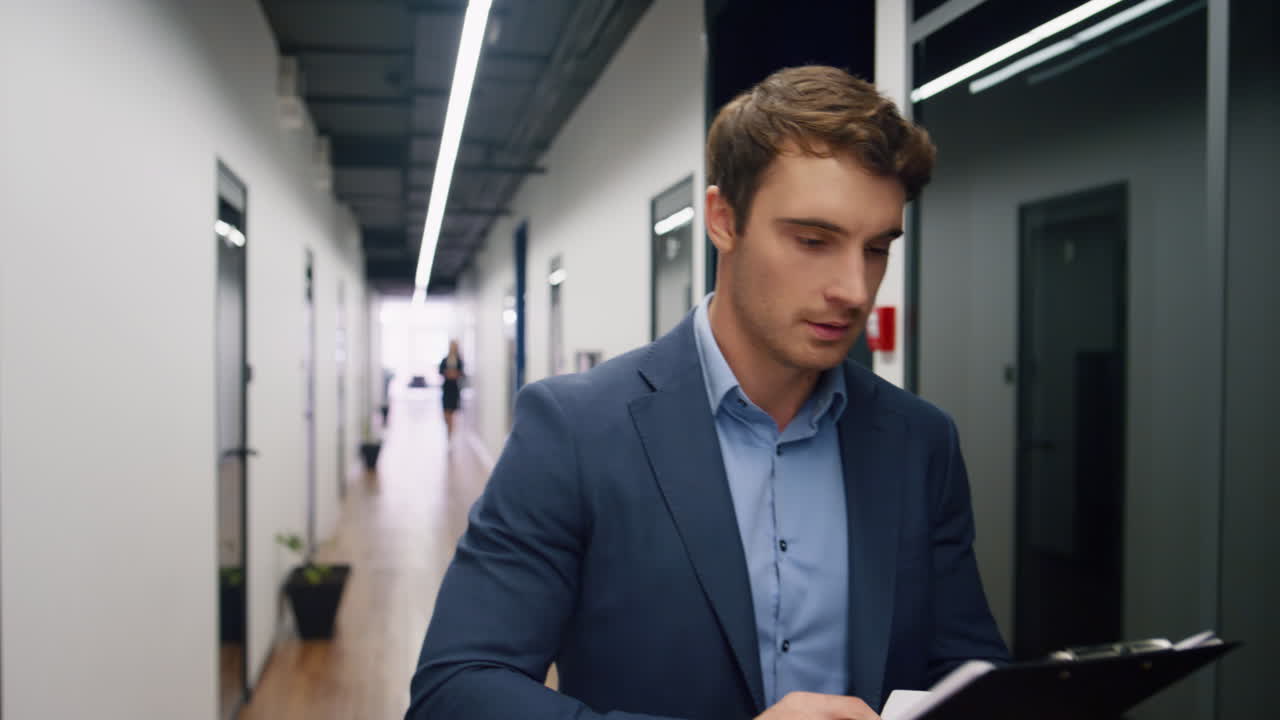 lavoratore felice che controlla i documenti sulla scheda. mentore d'ufficio che prende appunti camminando