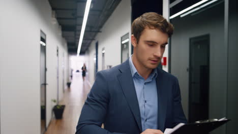 Happy-worker-checking-papers-on-clipboard.-Office-mentor-making-notes-walking