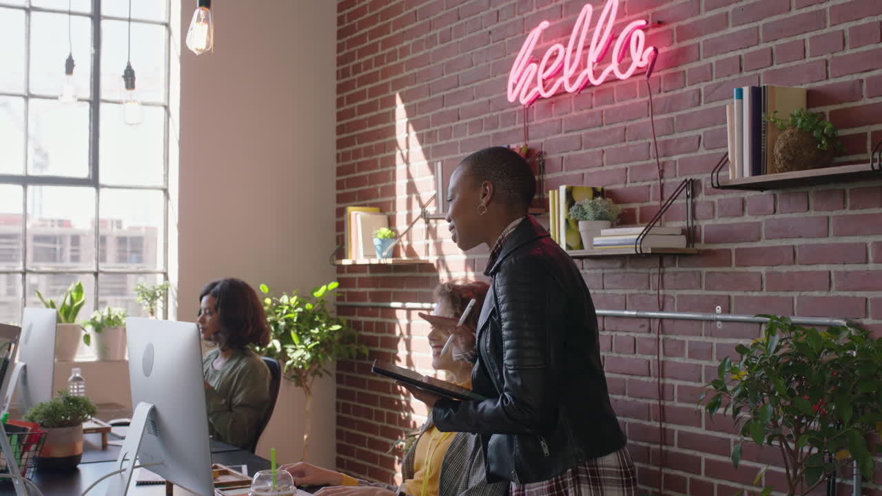 young african american business woman team leader enjoying management career checking colleagues working using tablet computer in diverse office workplace walking confident female manager