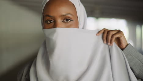 attractive arabian woman hides face with national headscarf