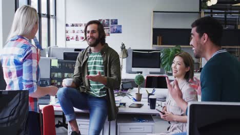 Diverse-office-colleagues-wearing-face-masks-discussing-together-at-modern-office