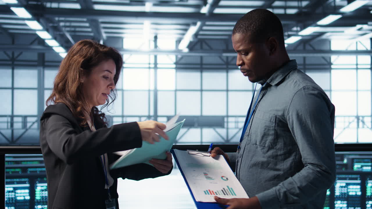 el equipo del centro de datos examina los archivos de papeleo en la sala del servidor, revisando el sistema.