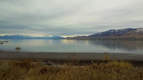 Vista-De-Un-Lago-Y-Un-Paisaje-Montañoso,-Luego-Retroceda-Y-Ascienda-A-Través-De-Los-árboles-Para-Revelar-Un-Paisaje-Más-Amplio