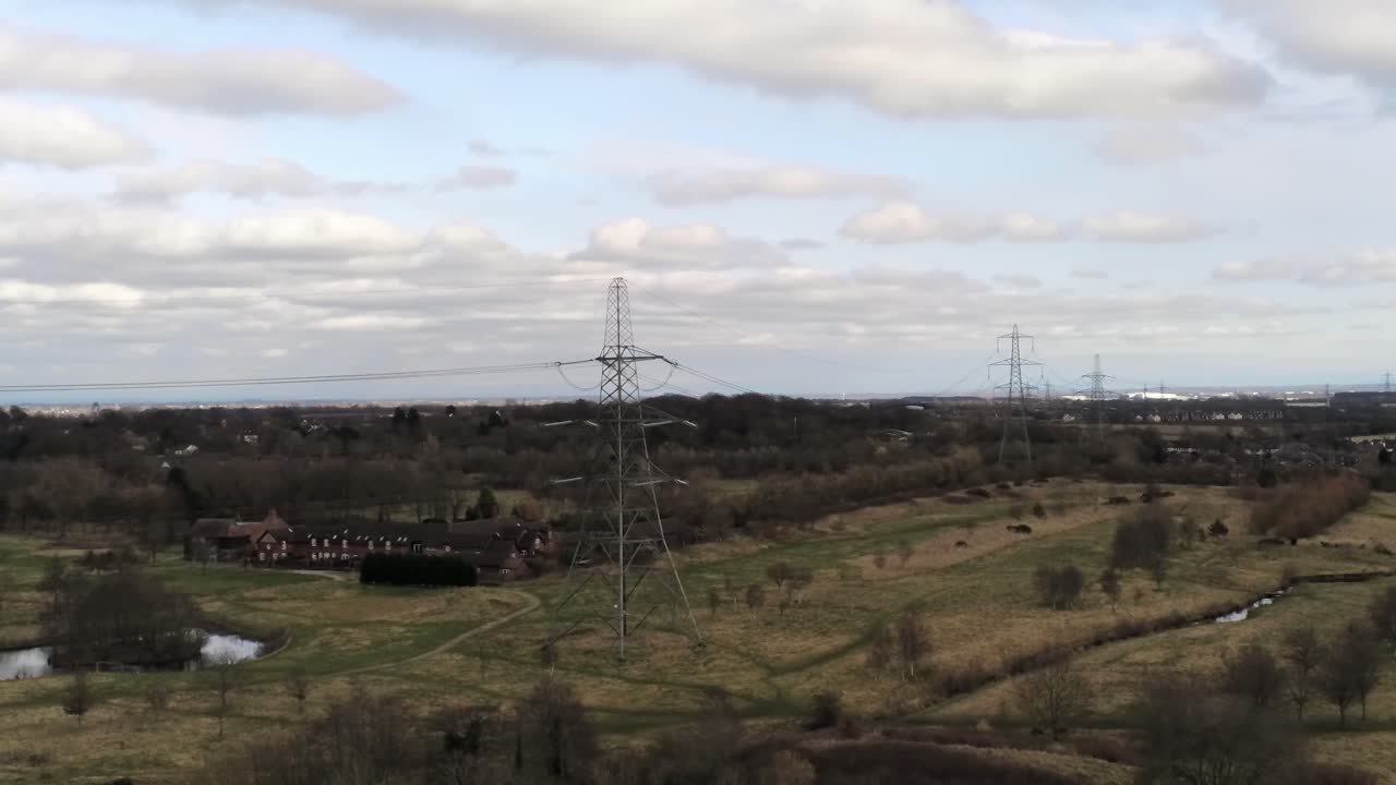 Descending aerial view Electricity distribution power pylon overlooking British parkland countryside
