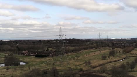 Absteigende-Luftaufnahme-Des-Stromverteilungsmastes-Mit-Blick-Auf-Die-Britische-Parklandschaft