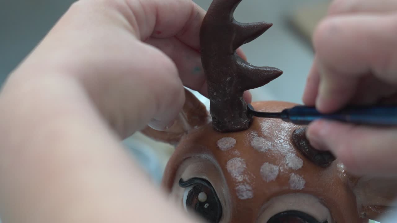 Primo piano di mani che attaccano le corna a una scultura di renna in un laboratorio artigianale.