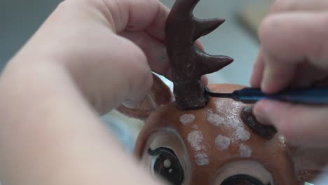 close-up of hands attaching antlers to a reindeer sculpture in a craft workshop