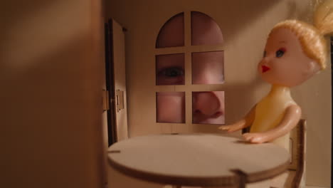 boy with cold stares through window of miniature dollhouse