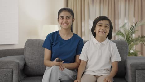 happy indian siblings watching tv