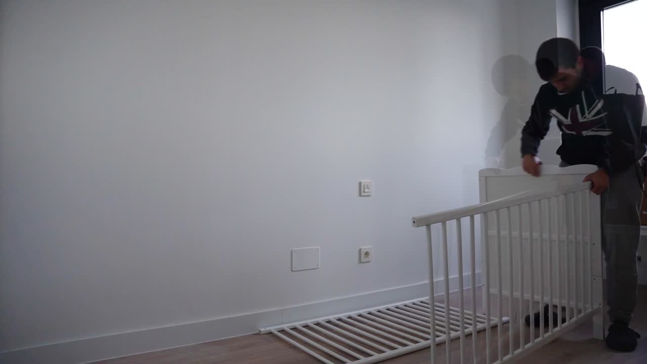 Man assembling a crib for the baby in fast motion finishing at night