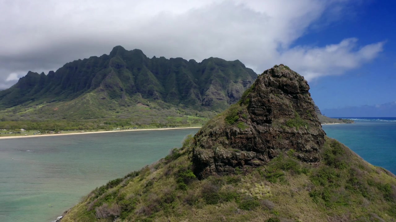 Ripresa aerea ravvicinata di media distanza che orbita attorno all'isola di Mokolii o Chinaman's Hat al largo della costa del parco regionale di Kualoa, sotto le montagne Koolau, Oahu, Hawaii.