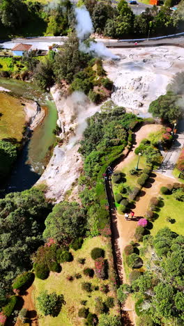 beautiful park on the sloping hill with a river at the foot. some steam rising from the ground in few spots. azores. aerial perspective. vertical video.