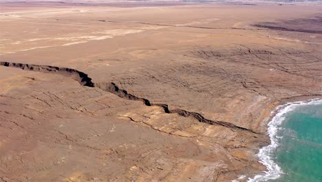aerial view of a large crack in a desert landscape next to a body of water