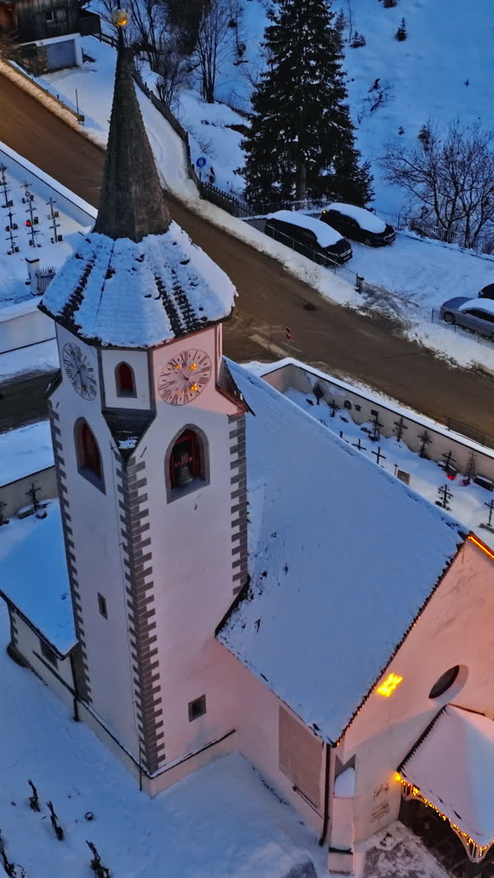 Aerial drone view of the Corvara village covered in snow at blue hour, in South Tyrol, Dolomites, in northern Italy. Vertical