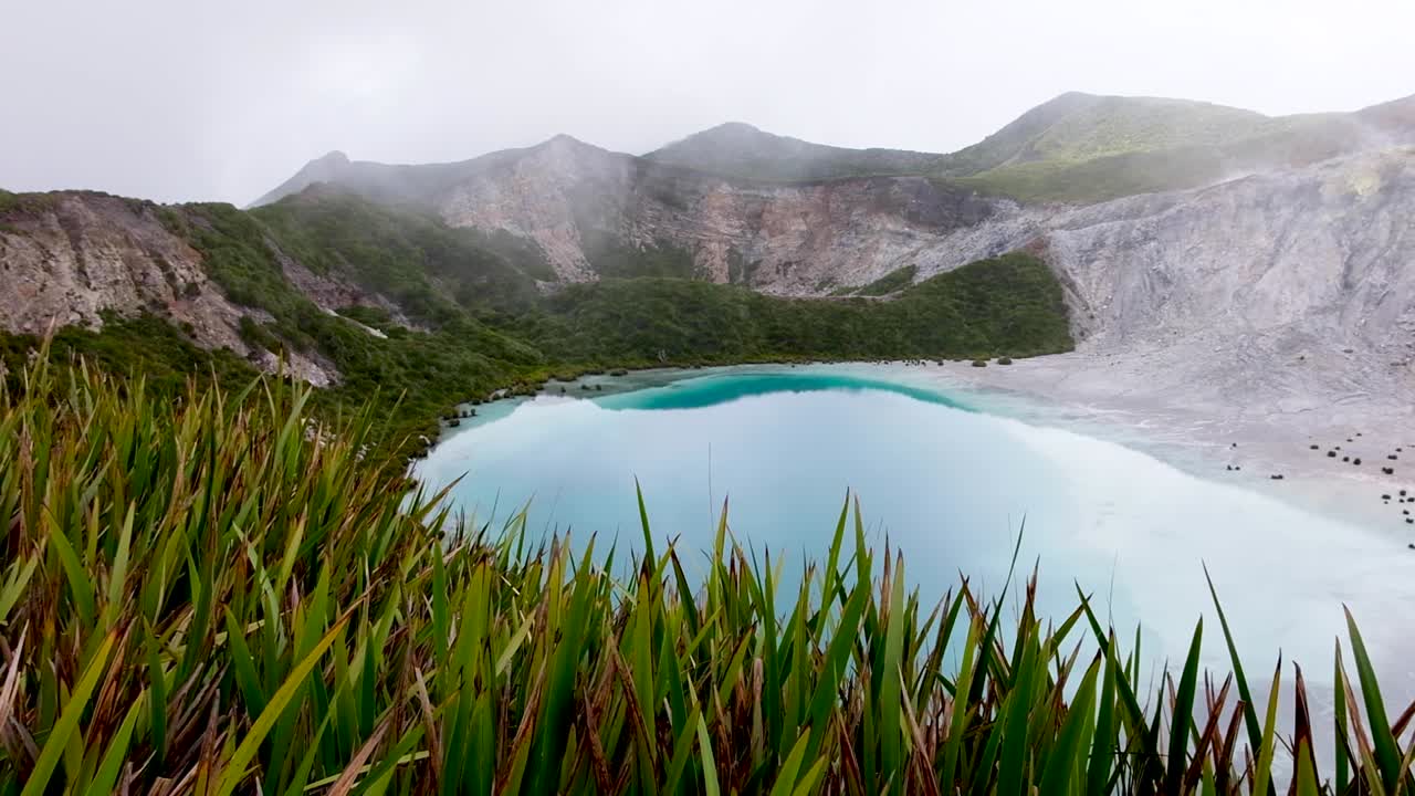 Stunning blue crater lake at volcanic summit Mt Balbi volcano on multi-day hike and climb in remote Bougainville, Papua New Guinea. Pan left to right