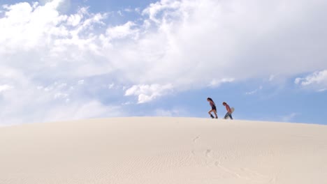 couple with sand boards walking on the sand dune 4k