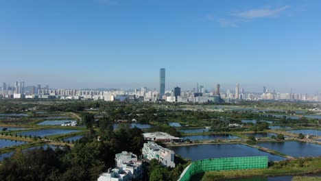 Hong-Kong-and-Shenzhen-border-line-over-Hong-Kong-rural-houses-with-Shenhzen-skyline-in-the-horizon,-Aerial-view