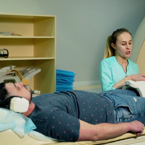 man in headphones lying on a bed in clinic. nurse takes of medical equipment from the patient. modern medical equipment in the hospital.