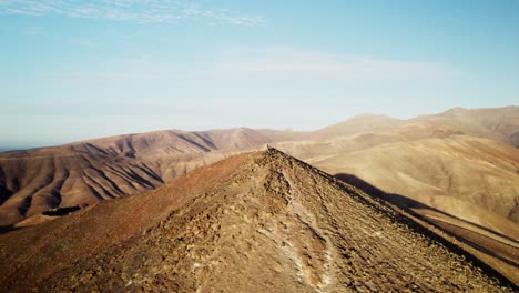 Barren,-undulating-hills-under-clear-skies-on-Fuerteventura-island,-aerial-view