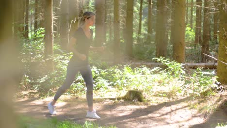 a pretty blonde woman wearing athletic apparel starts to run down a forest path